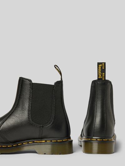 Produktfoto, Chelsea Boots aus echtem Leder mit Label-Patch von Dr. Martens, schwarze Farbe, abgerundete Passform, profilierte Sohle, Absatzhöhe 4 cm, Schafthöhe 14 cm, Schaftweite 10 cm, gelbe Nähte und Label-Patch, seitliche Gummieinsätze, Kontrastsohle, Damenmodell.