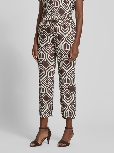 Frauenmodel trägt Stoffhose mit Bindegürtel Modell 'Pia' von TONI aus reiner Viskose, braun-weißes Allover-Muster, Wide Fit, 7/8-Länge, Nahaufnahme Oberkörper.