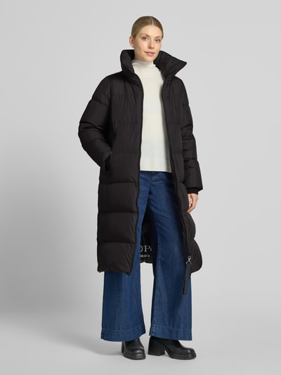 Vrouwenmodel draagt Regular Fit lange donsjas met afneembare rugzakriemen van Marc O'Polo in zwart met lichte textuur, dames, volledig frontaal.