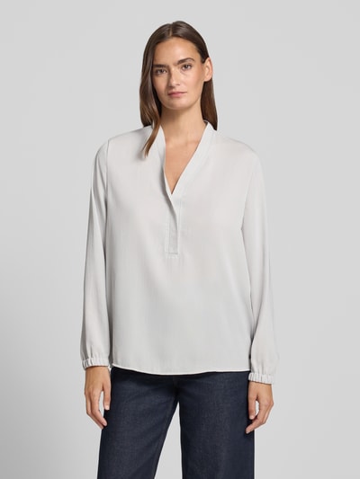 Kobiece model prezentuje Regular Fit Bluse mit V-Ausschnitt von Marc Cain, jasna bluzka o kroju regular fit z dekoltem w serek, detal z logo, długość tyłu w rozmiarze 36: 65 cm, długość rękawów w rozmiarze 36: 59 cm, przód, całkowity widok.