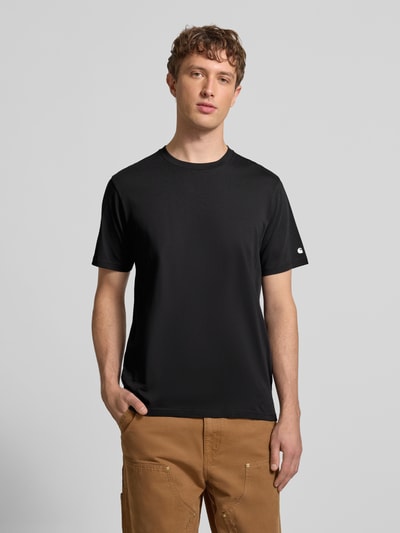 Männermodel trägt schwarzes T-Shirt mit geripptem Rundhalsausschnitt von Carhartt Work In Progress, reine Baumwolle, Regular Fit, Ganzkörperansicht von vorne.
