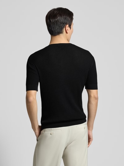 Männermodel trägt Slim Fit T-Shirt mit Seiden-Anteil in Strick-Optik von Emporio Armani, Schwarz, elastische Abschlüsse, Ganzkörperansicht Rückansicht.