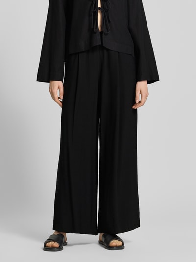 Frauenmodel trägt Wide Fit Stoffhose aus Viskose-Mix Modell 'Frencis' von STEHMANN in Schwarz mit elastischem Bund, Nahaufnahme Unterkörper.