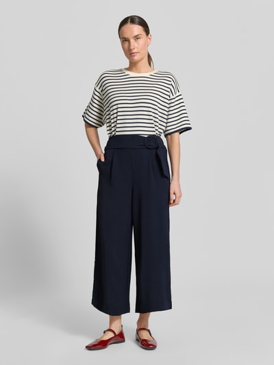 Vrouwenmodel draagt Wide Fit Stoffhose met bandplooien van Zero, donkerblauwe stoffen broek, siergesp, verkorte pasvorm, comfortband, bandwijdte maat 36: 34 cm, binnenbeenlengte maat 36: 61 cm, wide fit, vooraanzicht volledig lichaam.