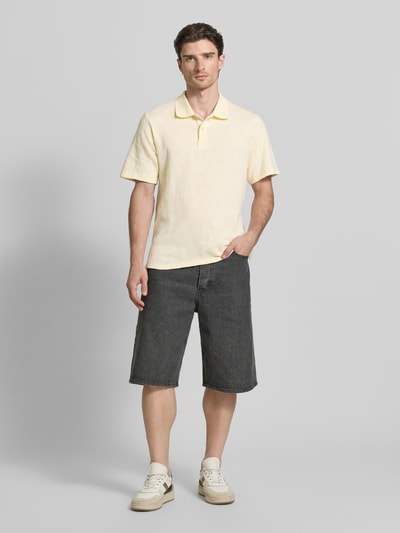 Männermodel trägt Regular Fit Poloshirt mit Knopfleiste Modell 'Gabriel' von Wood Wood aus Reine Baumwolle in Hellgelb, Ganzkörperansicht von vorne. Rückenlänge bei Größe M: 70 cm.