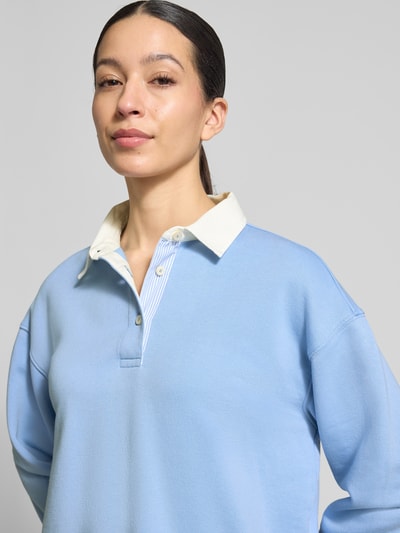 Frauenmodel trägt Longsleeve mit Polokragen und kurzer Knopfleiste von Gant in Hellblau, Baumwoll-Mix, Nahaufnahme Oberkörper.