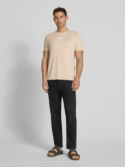 Männermodel trägt Regular Fit T-Shirt aus reiner Baumwolle von s.Oliver RED LABEL in Unifarbe mit Label Print, Ganzkörperansicht von vorne.