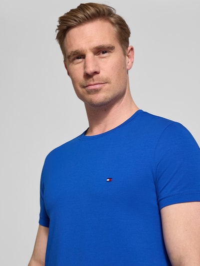 Männermodel trägt Slim Fit T-Shirt aus Baumwoll-Mix von Tommy Hilfiger in Optik: Unifarben mit Logo-Detail, Rundhals, Kurzarm, Nahaufnahme Oberkörper.
