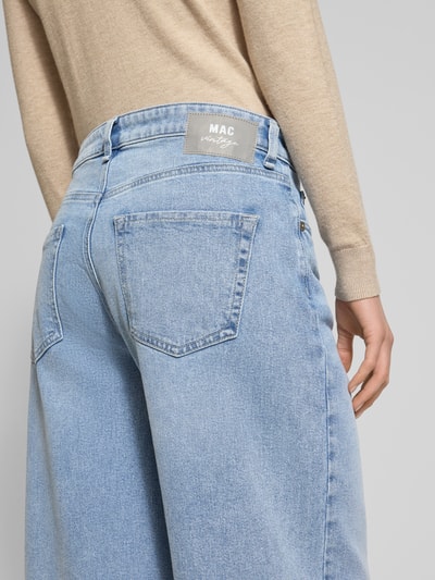 Frauenmodel trägt Loose Fit Jeans aus Baumwoll-Mix Modell 'Nevada' von MAC in Hellblau, mit Label-Patch und ausgefransten Beinabschlüssen, Detailaufnahme Rückansicht.