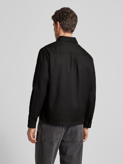 Männermodel trägt Regular Fit Hemdjacke aus Lyocell-Baumwoll-Mix Modell 'ENOCK' von HUGO, unifarben schwarz, Ganzkörperansicht Rückansicht.