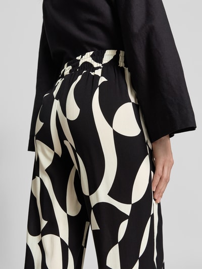 Frauenmodel trägt Stoffhose aus Viskose im Allover-Look Modell 'CHANISE' von Soyaconcept, Relaxed-Fit, Ganzkörperansicht Rückansicht. Bundweite 35 cm, Innenbeinlänge 76 cm bei Größe S.