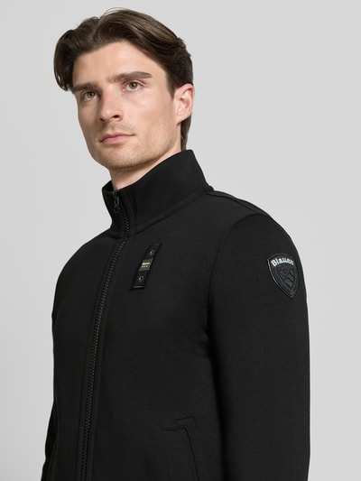 Männermodel trägt Sweatjacke mit Stehkragen Modell 'City New' von Blauer Usa, Schwarz, Baumwoll-Mix, Slim-Fit, Label-Detail, Nahaufnahme Oberkörper.