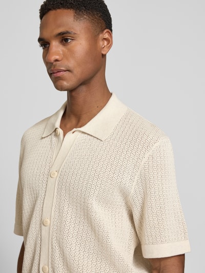 Männermodel trägt Regular Fit Freizeithemd in Strick-Optik Modell 'Owen' von Jack & Jones Premium, Reine Baumwolle, Semitransparent, Kurzärmelig, Kentkragen, durchgehende Knopfleiste, Beige, fein strukturierte Oberfläche, Nahaufnahme Oberkörper.