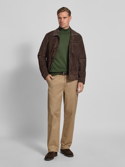 Männermodel trägt Rollkragenpullover aus Schurwolle von MAERZ Muenchen in Grün, lockerer Schnitt, gerippte Abschlüsse, Label-Detail, Ganzkörperansicht von vorne.