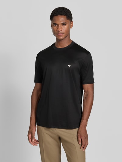 Männermodel trägt T-Shirt aus Lyocell-Mix mit Label-Stitching von Emporio Armani, schwarze Farbe, taillierte Passform, Ganzkörperansicht von vorne.