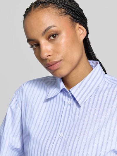 Vrouwenmodel draagt Hemdbluse aus reiner Baumwolle van Victoria Beckham in relaxed fit met overhemdkraag en borstzak, lichtblauw met witte streepjes, puur katoen, langemouwen, ruglengte bij maat 36: 69 cm, mouwlengte bij maat 36: 59 cm, close-up bovenlichaam.