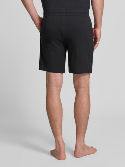 Männermodel trägt Regular Fit Sweatshorts aus Baumwoll-Mix Modell 'NOAH' von HUGO in Schwarz, Sweatmaterial, Ganzkörperansicht Rückansicht.