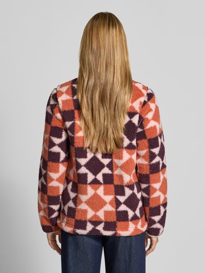 Männermodel trägt Regular Fit Jacke mit Stehkragen von Columbia, materiał z polaru, wzór geometryczny w pomarańczowym, fioletowym i kremowym kolorze, krój regular fit, kieszenie napoleonki i boczne, zamek błyskawiczny, długość tyłu w rozmiarze S: 61 cm, szerokość ramion w rozmiarze S: 39 cm, szerokość klatki piersiowej w rozmiarze S: 49 cm, długość rękawa w rozmiarze S: 63 cm, widok całej sylwetki z tyłu.