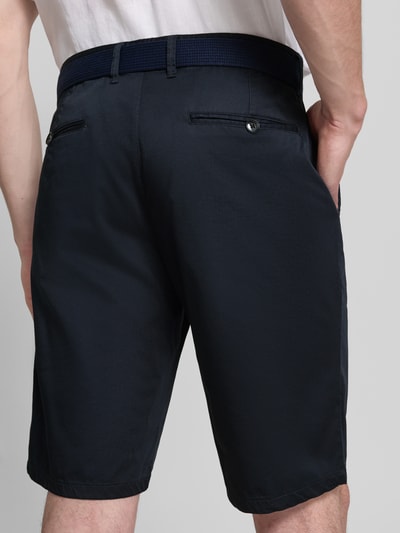 Männermodel trägt Bermudas aus Light Baumwolle mit Gürtel von Christian Berg Men, dunkle Farbe, Gesäßtaschen, Ganzkörperansicht Rückansicht