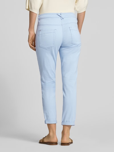 Frauenmodel trägt Tapered Fit Chino aus Baumwoll-Mix von Tom Tailor, Optik: Unifarben, Passform: Tapered-Fit, Low Waist, Cropped, 5-Pocket-Design, Label-Prägung, Webstruktur, Farbe Hellblau, Ganzkörperansicht Rückansicht.