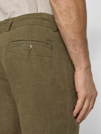 Männermodel trägt Leinenshorts mit Bindegürtel und Gesäßtaschen von MCNEAL in Khaki mit Label-Stitching, Detailaufnahme Rückansicht. Reines Leinen, Straight Fit, Knopf- und Reißverschluss, Bundweite bei Größe M 45 cm, Innenbeinlänge 16 cm, Gesäßleistentasche.