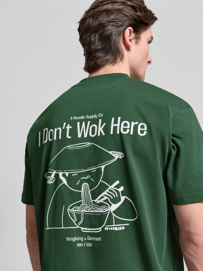 Mężczyzna nosi T-Shirt mit Label-Print Modell 'Baine' von WOODBIRD, bawełna, krój regular fit, zielony, z nadrukiem na plecach, widok z tyłu