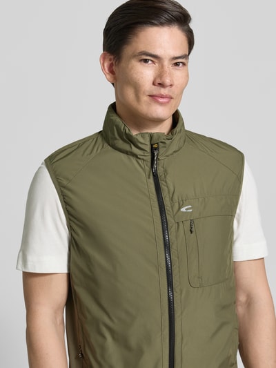 Männermodel trägt Regular Fit Weste mit gefüttertem Stehkragen von camel active in Olivgrün, mit Brusttasche, Reißverschluss und Eingrifftaschen, Nahaufnahme Oberkörper.