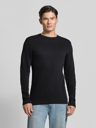 Männermodel trägt Regular Fit Longsleeve aus reiner Baumwolle Modell 'Basic' von Lindbergh in Schwarz, Jeans, Ganzkörperansicht von vorne. Rückenlänge bei Größe M: 73 cm, Rundhalsausschnitt, Herren Longsleeve.