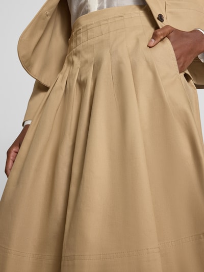 Frauenmodel trägt Knielanger Rock aus reiner Baumwolle von Tommy Hilfiger in Beige mit glatter Textur, Nahaufnahme Oberkörper.