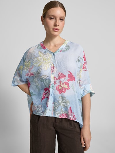 Kobiece model prezentuje Relaxed Fit Bluse aus Viskose-Mix im Allover-Look von comma, mieszanka wiskozy, krój relaxed fit, wzór na całej powierzchni, dekolt w serek, rękaw o dł. 3/4, wydłużony tył, listwa guzikowa, długość tyłu w rozmiarze S: 64 cm, długość rękawa w rozmiarze S: 24 cm, jasnoniebieskie tło z wielobarwnym wzorem kwiatowym, lekko błyszcząca powierzchnia, całkowity widok z przodu