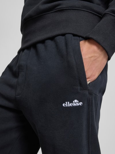 Männermodel trägt Sweatpants mit Logo-Stitching Modell 'ORVINIO' von Ellesse aus Baumwoll-Mix in Schwarz, Nahaufnahme Oberkörper.