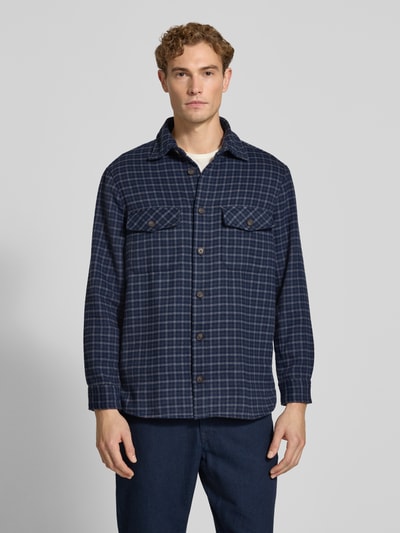 Männermodel trägt Regular Fit Overshirt mit Karo-Muster von Christian Berg Men in Dunkelblau mit Knopfleiste, Ganzkörperansicht von vorne. Herren Freizeithemd