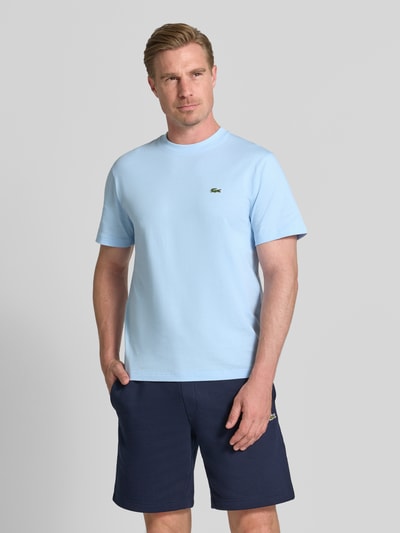 Männermodel trägt Regular Fit T-Shirt aus reiner Baumwolle von Lacoste in Hellblau, weiche Textur, Herren T-Shirt, Ganzkörperansicht von vorne.