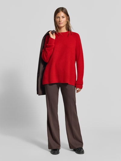 Frauenmodel trägt Regular Fit Pullover aus reinem Kaschmir in Strick-Optik von MYON in Rot, kombiniert mit brauner Hose, Ganzkörperansicht von vorne. Rückenlänge bei Größe 36: 68 cm, Ärmellänge: 66 cm, Rundhalsausschnitt, weiche Textur.