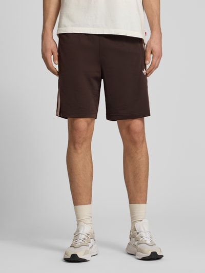 Männermodel trägt Regular Fit Sport-Shorts mit Kontraststreifen Modell 'FIREBIRD' von adidas Originals, Optik: Unifarben, Logo-Stitching, elastischer Bundabschluss, Tunnelzug innen, seitliche Reißverschlusstasche, Ganzkörperansicht von vorne.