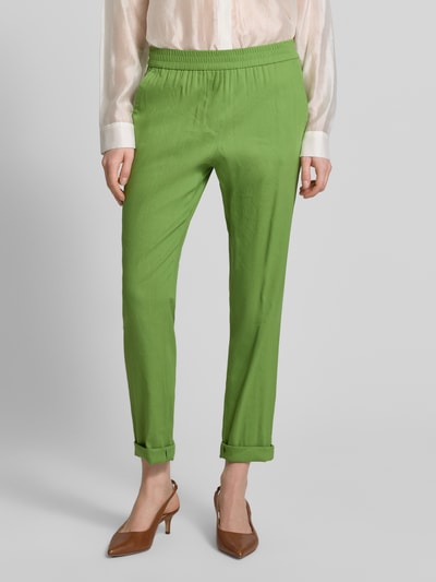 Frauenmodel trägt Stoffhose aus Leinen-Mix mit französischen Eingrifftaschen von Marc Cain in Grün mit Straight Fit und Aufschlag; Nahaufnahme Oberkörper. Leinen-Mix mit Viskose-Anteil, elastischer Bund, Gesäßtaschen, Bundweite bei Größe 36: 37 cm, Innenbeinlänge bei Größe 36: 70 cm.