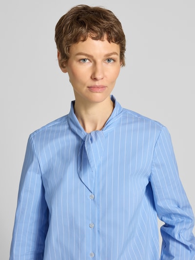Vrouwenmodel draagt Slim Fit Schluppenbluse mit Knopfleiste van Stefanel, lichtblauw met witte strepen, katoenmix, staande kraag, knoopsluiting, stretch, halve lichaamsopname vooraan.