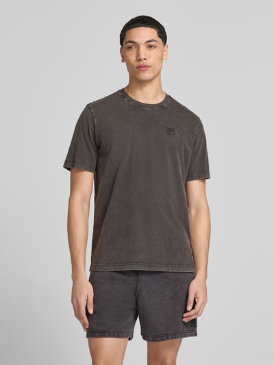 Męski model trägt T-Shirt mit Label-Stitching und Rundhalsausschnitt von CHAMPION, bawełna, krój regular fit, długość tyłu w rozmiarze M: 67 cm, ciemnoszary kolor, miękka faktura, Ganzkörperansicht von vorne.
