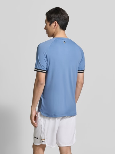 Männermodel trägt Regular Fit T-Shirt mit Label Print Modell 'TOC SERVE 2' von BOSS Green in hellblau mit Kontraststreifen, glatte Textur, Ganzkörperansicht Rückansicht.