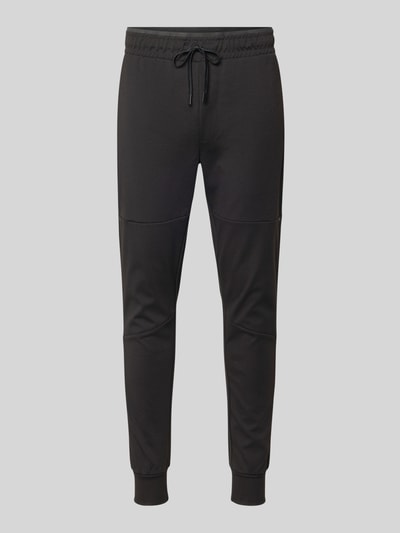Produktfoto, spodnie dresowe z elastycznej mieszanki materiałów z domieszką bawełny model 'GORDON' od Jack & Jones, krój slim fit, elastyczny pas z tunelem, elastyczne zakończenia nogawek, boczne kieszenie zapinane na zamek błyskawiczny, długość wewnętrzna nogawki w rozmiarze m: 73 cm, czarny kolor, gładka tekstura