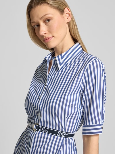 Kobiece modelka nosi Hemdblusenkleid mit Gürtel Modell 'Dominique2' od JOOP!, niebiesko-białe paski, bawełniany miks ze stretchem, krój slim fit, guzik, pasek, 1/2 rękaw, szerokość w rozmiarze 36: 43 cm, długość tyłu: 100 cm, długość rękawa: 31 cm, półzbliżenie górnej części ciała.