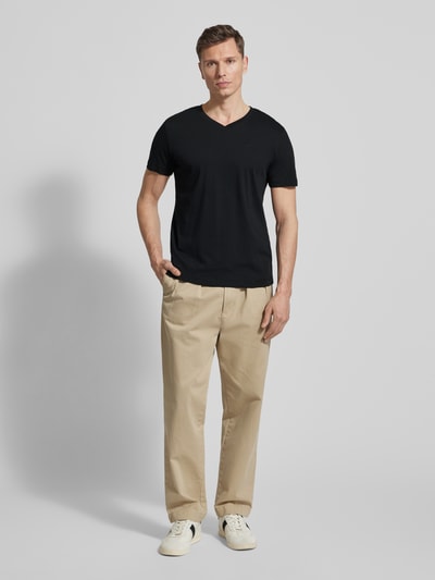 Männermodel trägt Regular Fit T-Shirt aus reiner Baumwolle von Tom Tailor, unifarben schwarz, Logo-Stitching, Ganzkörperansicht von vorne.
