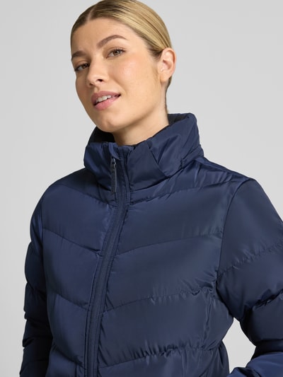 Vrouwenmodel draagt donkerblauwe gewatteerd jack in regular fit met opstaande kraag, steekzakken, ritssluiting, Model 'Synria' van Cars Jeans. Nahaufnahme Oberkörper. Ruglengte maat S: 65 cm, schouderbreedte: 42 cm, borstwijdte: 50 cm, mouwlengte: 70 cm.