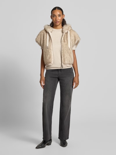 Frauenmodel trägt Regular Fit Weste aus Kunstfell von Marc Cain, beige Töne, weiche Fellstruktur, dezente Kontraste, Ganzkörperansicht von vorne.