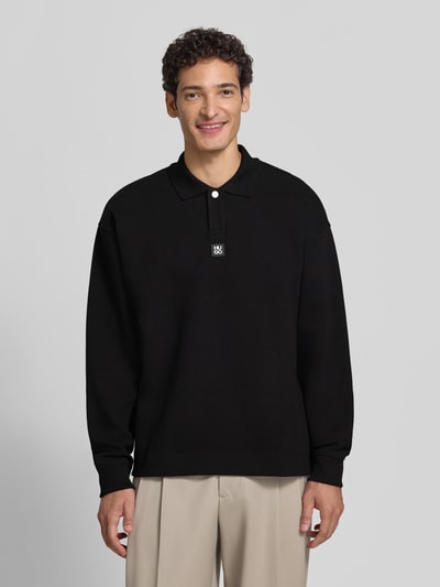 Męski model nosi czarną bluzę z mieszanki bawełny Oversize Fit Sweatshirt aus Baumwoll-Mix model 'Dabins' od HUGO, Ganzkörperansicht von vorne. Bluza męska HUGO