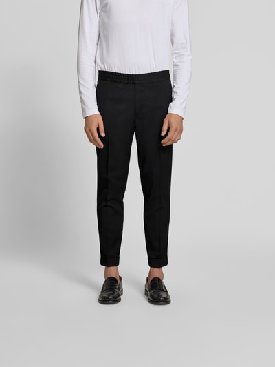 Männermodel trägt Slim Fit Anzughose mit Woll-Anteil von Filippa K, Elastischer-Material-Mix, Eingrifftaschen, Bundfalten, Ganzkörperansicht von vorne.