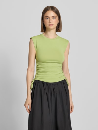 Frauenmodel trägt Trägertop mit seitlichen Raffungen Modell 'GURI' von Topshop aus Baumwoll-Elasthan-Mix, Slim-Fit, Rundhalsausschnitt, Rückenlänge bei Größe S: 54 cm, in hellem Grün mit glatter Textur, Ganzkörperansicht von vorne.