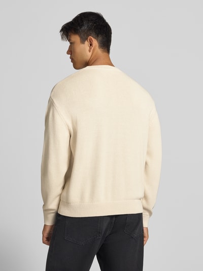 Männermodel trägt Relaxed Fit Strickpullover aus reiner Baumwolle von REVIEW, helle Farbe, gerippte Abschlüsse, Ganzkörperansicht Rückansicht.