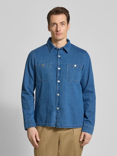 Męski model nosi Hemdjacke aus Baumwoll-Leinen-Mix in Denim-Optik von MAERZ Muenchen, mieszanka bawełny i lnu, krój regular fit, imitacja denimu, kołnierzyk typu kent, listwa guzikowa, kieszenie na piersi, długość tyłu w rozmiarze 50: 71 cm, widok całej sylwetki z przodu.