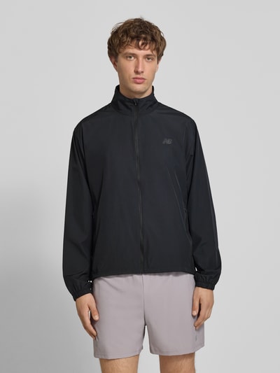 Männermodel trägt Regular Fit Jacke in Stehkragen Modell 'Fast Days' von New Balance, schwarz, Reißverschlusstaschen, Ganzkörperansicht von vorne.
